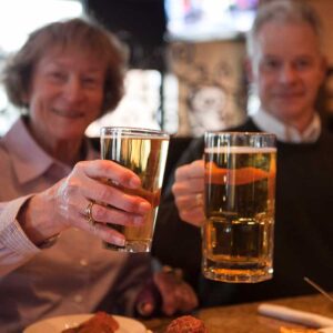 Couple cheers beer glasses and mugs at Cables Pub and Grill Greeley, Colorado restaurant and bar